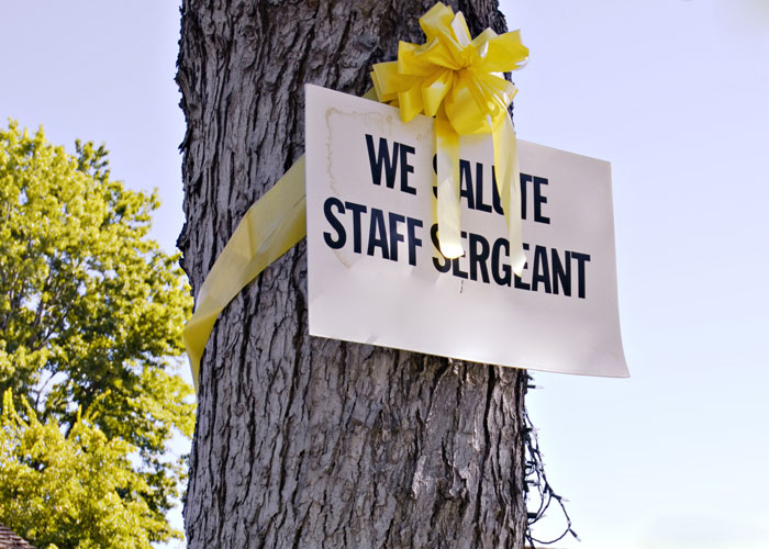 Yellow Ribbon tied around a tree with a sign saluting Staff Sergeant