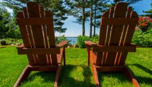 2 Adirondack chairs sitting side by side in the green grass on a sunny summer day overlooking Lake Wissota.